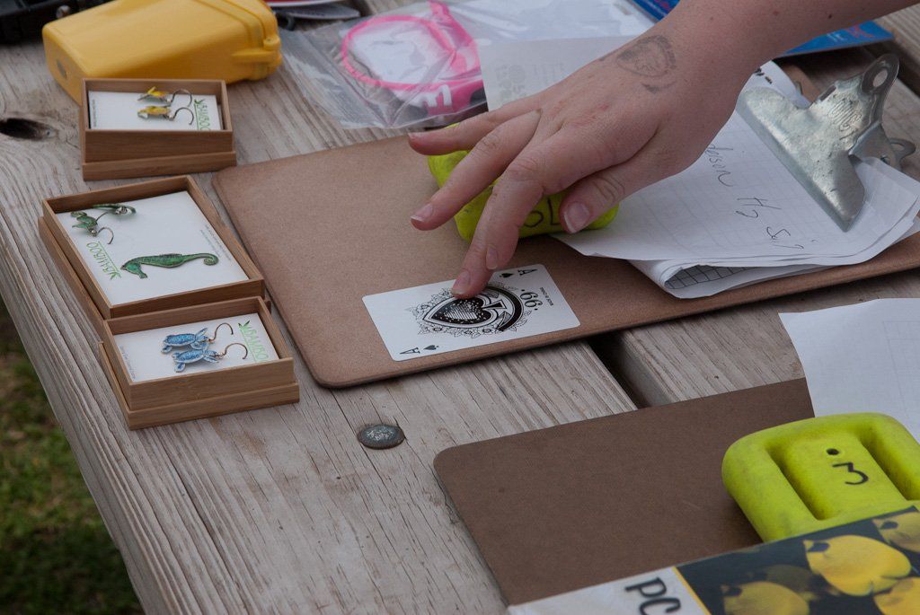 Hand pointing at a sticker on a wooden surface with small framed art and other objects.