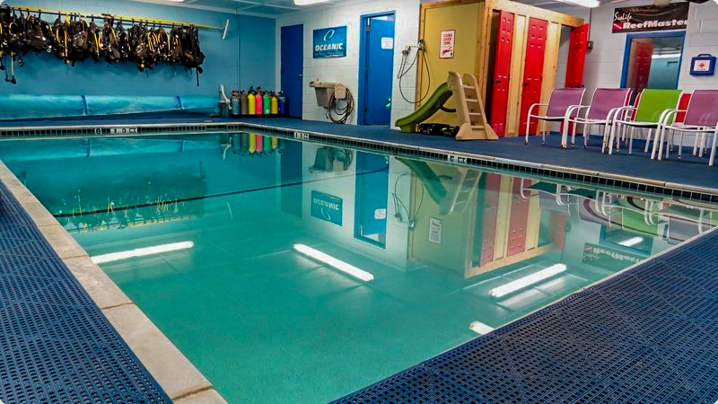 Indoor swimming pool with turquoise water, blue surroundings, and diving gear.