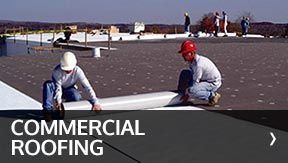 Two workers installing commercial roofing on a flat rooftop.