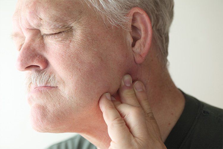 Middle age man holding jaw