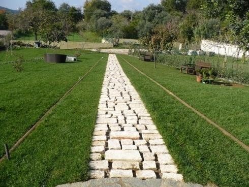 Un sentiero in pietra, realizzato con lastre rettangolari di colore chiaro, si estende al centro di un prato verde ben curato.