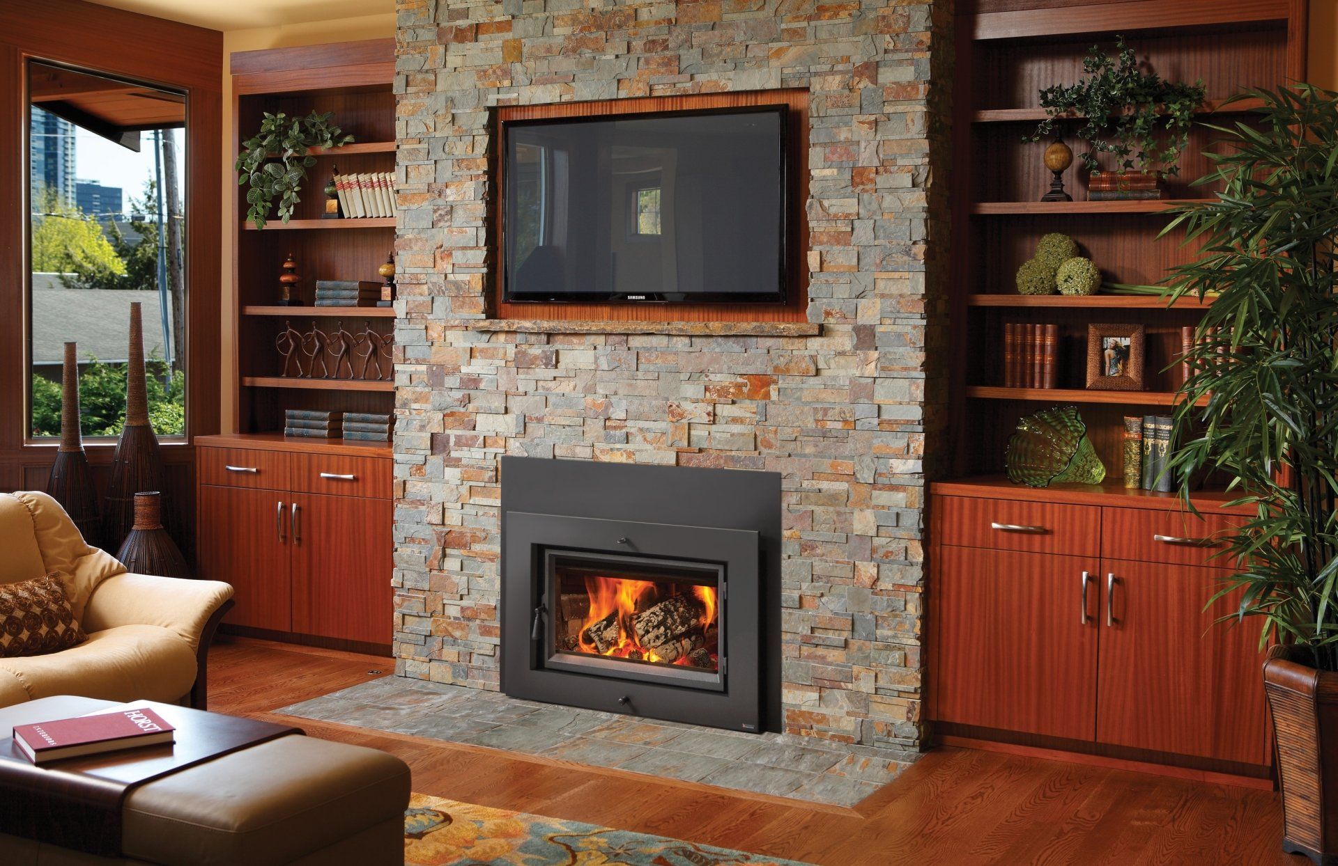 Living room with stone fireplace, built-in shelves, TV, and lit fire.