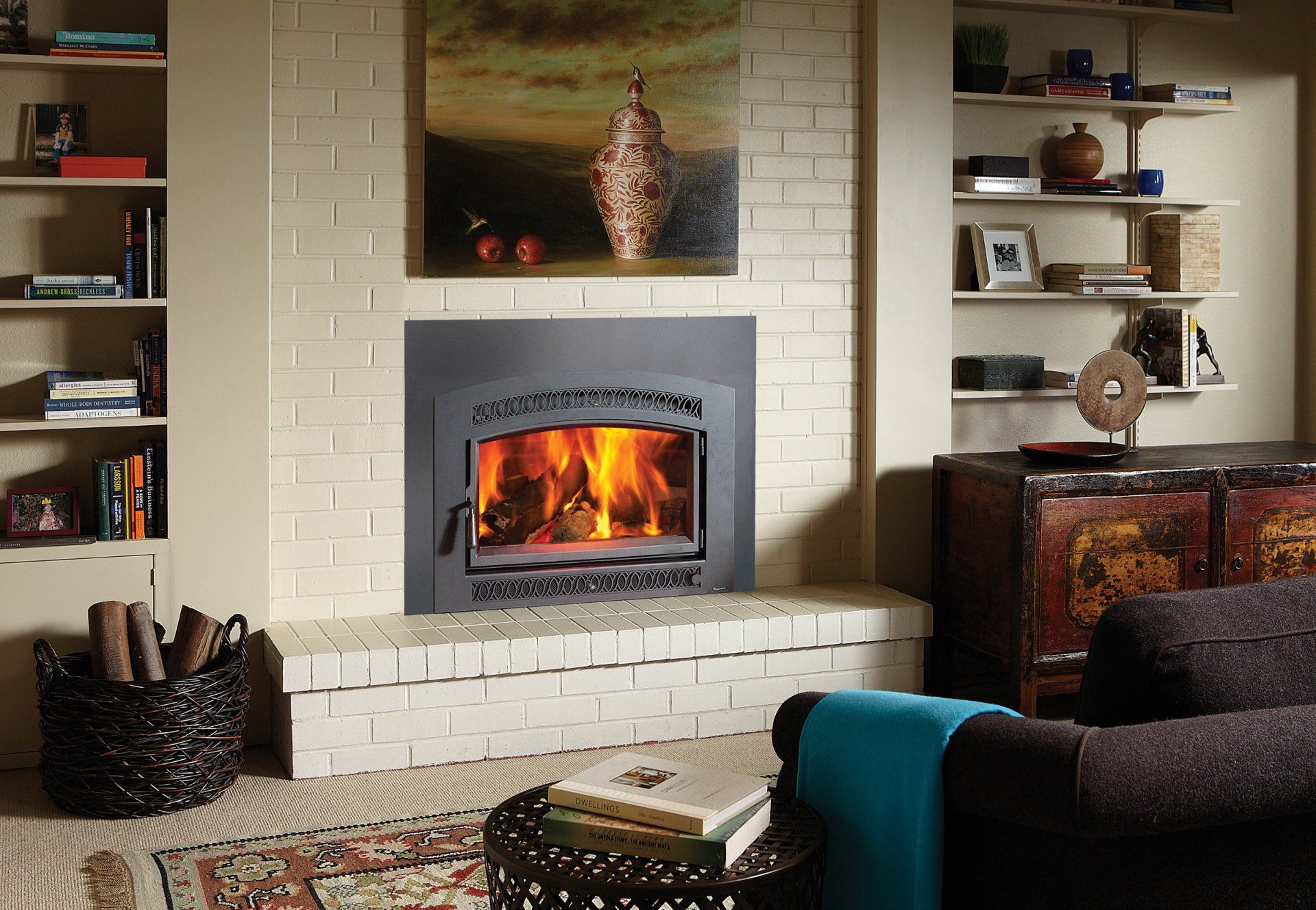 Fireplace with flames in a brick surround, flanked by bookshelves and a couch.