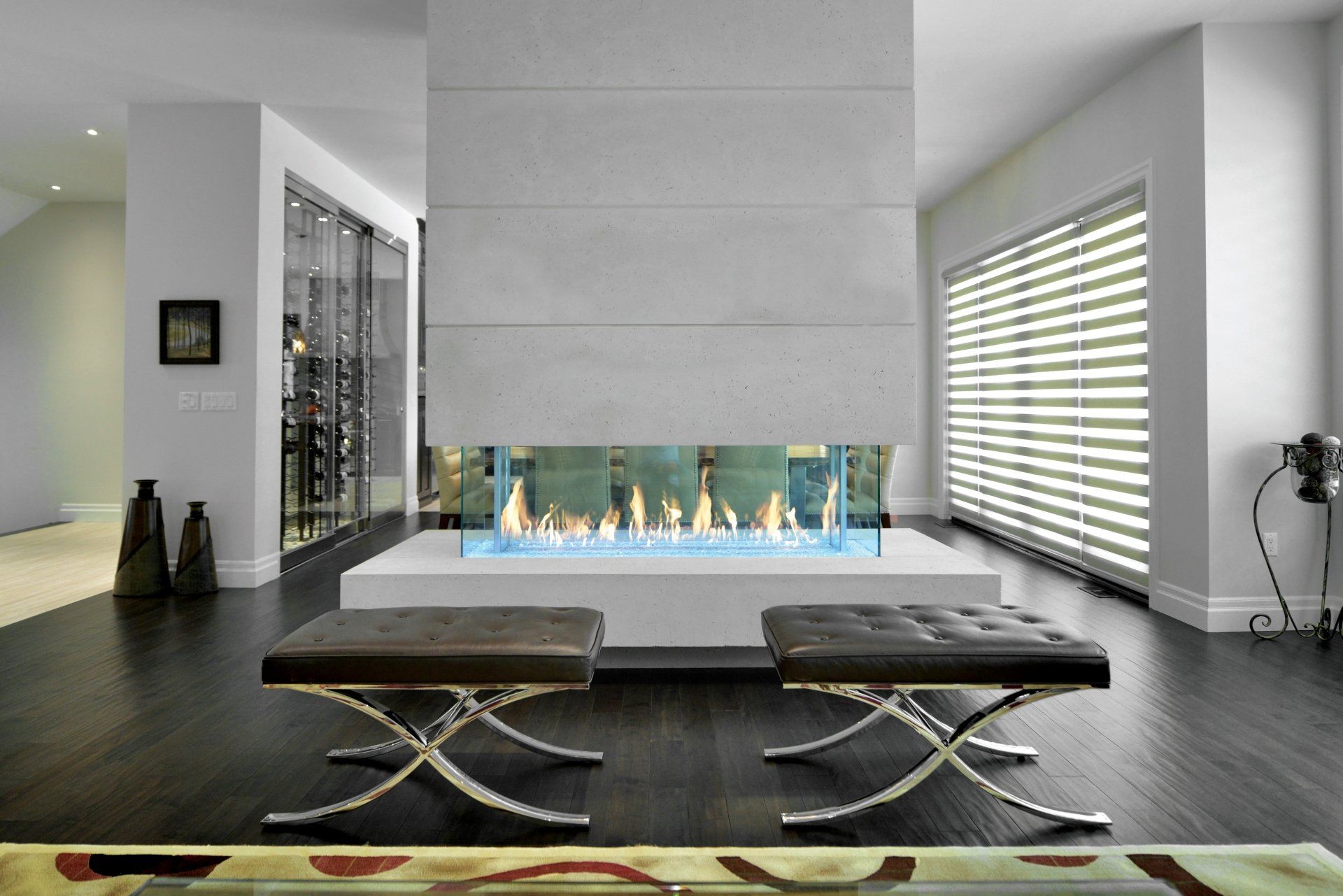 Modern living room with a linear fireplace, dark floor, and two leather ottomans.
