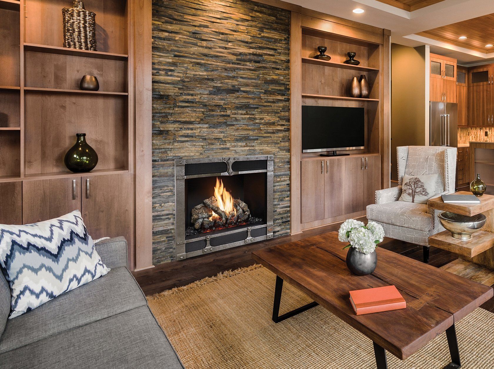 Living room with fireplace, built-in shelving, TV, wooden coffee table, and patterned pillow on a couch.