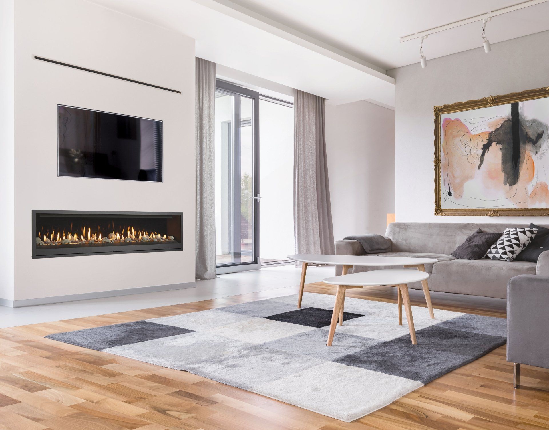 Modern living room with fireplace, TV, grey rug, sofa, artwork, and wooden floor.