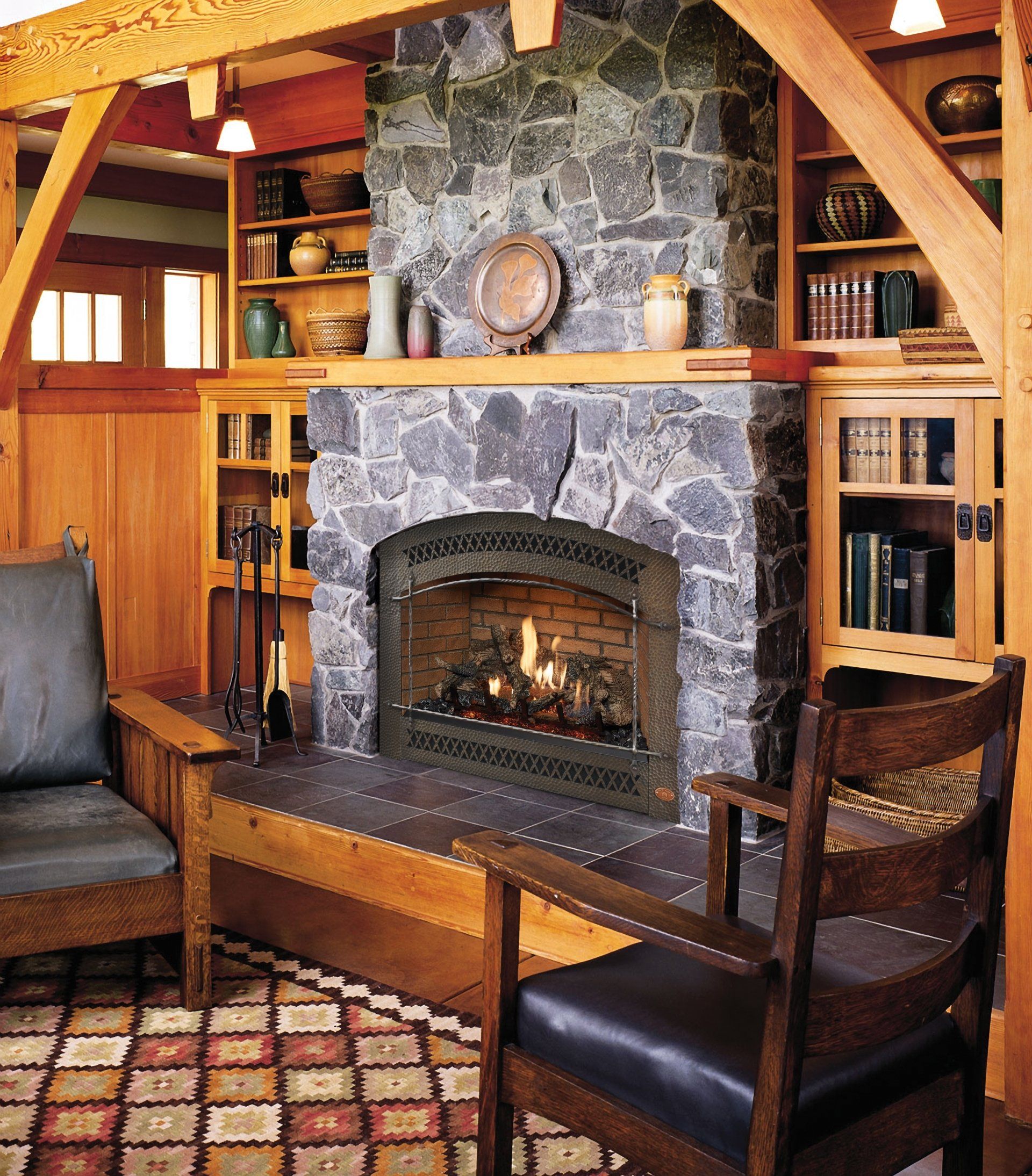 Cozy room with stone fireplace, wood beams, built-in bookshelves, and two armchairs.