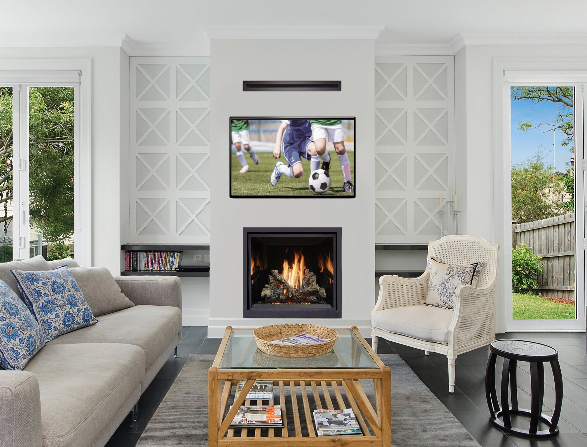 Living room with fireplace, TV, sofa, and armchair. Bright, neutral color palette, natural light. Soccer game on TV.