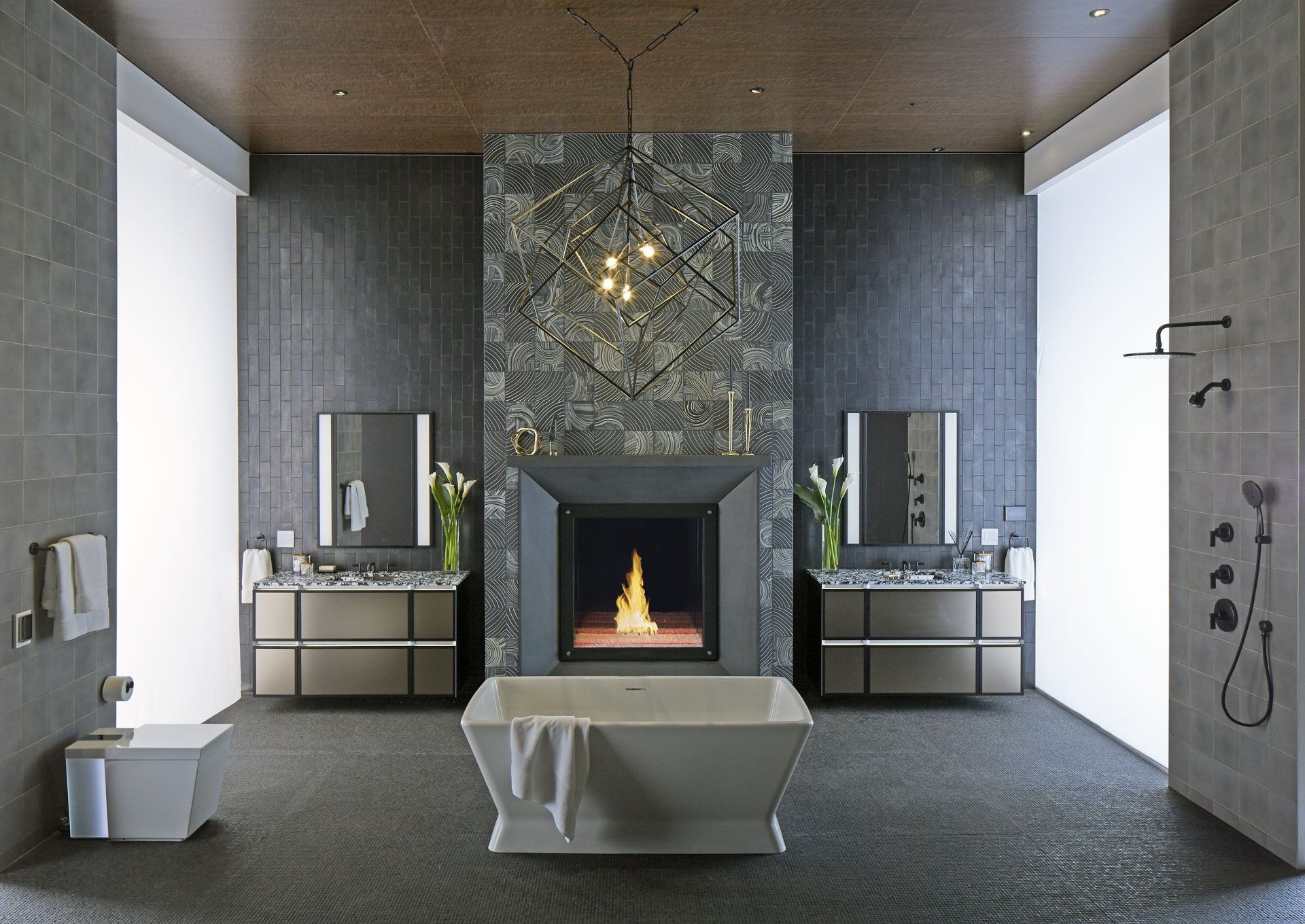 Luxury bathroom with fireplace, two vanities, and a freestanding tub. Gray tiles, dark wood ceiling, modern lighting.