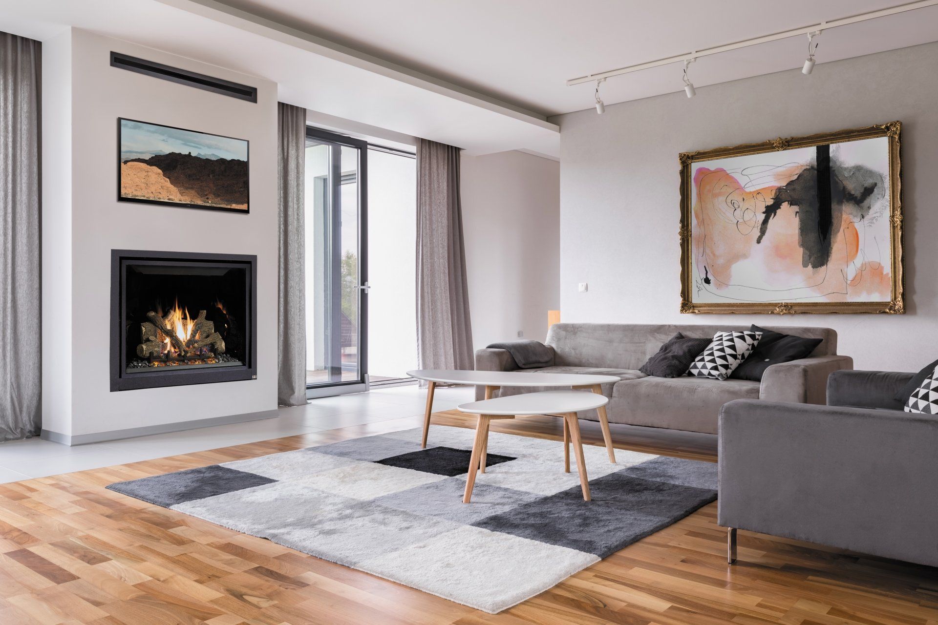 Modern living room with fireplace, gray sofa, abstract art, and wood flooring.