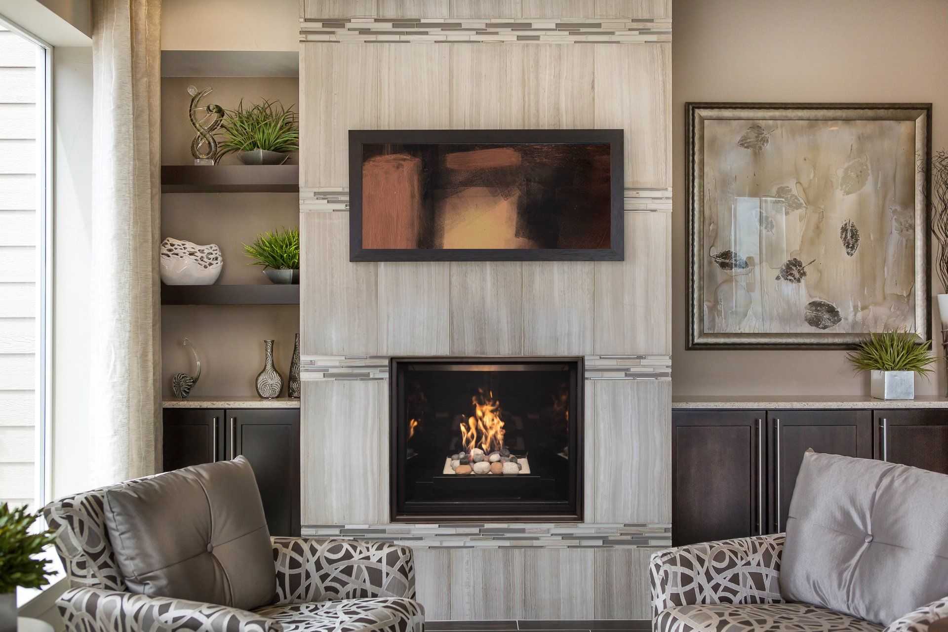 Living room with fireplace, built-in shelves, artwork, and seating with patterned upholstery.