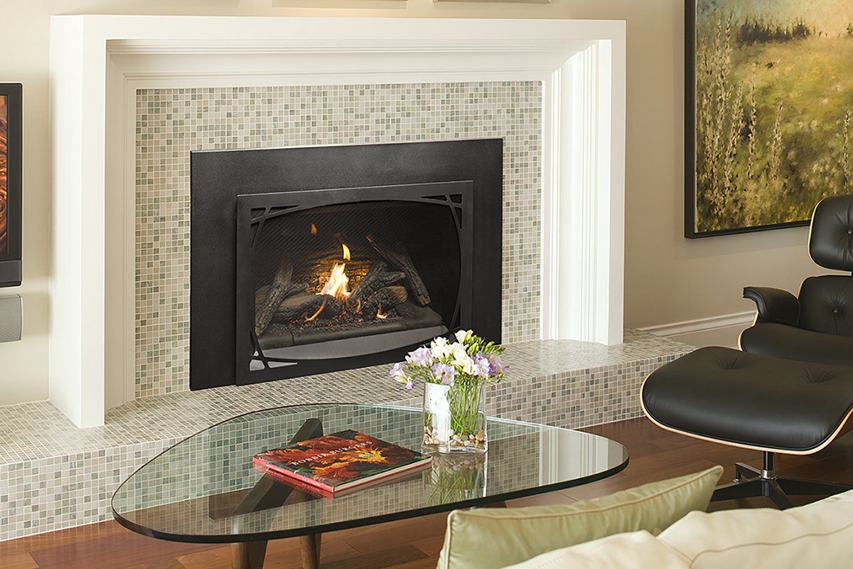 Fireplace with lit flames, surrounded by light-colored tile and white mantel. Oval glass coffee table with flowers.