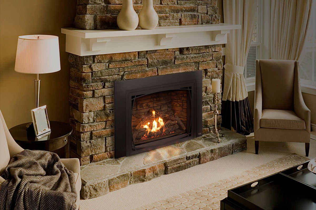 Fireplace with flames, surrounded by a stone facade, white mantel, and cozy living room setting.