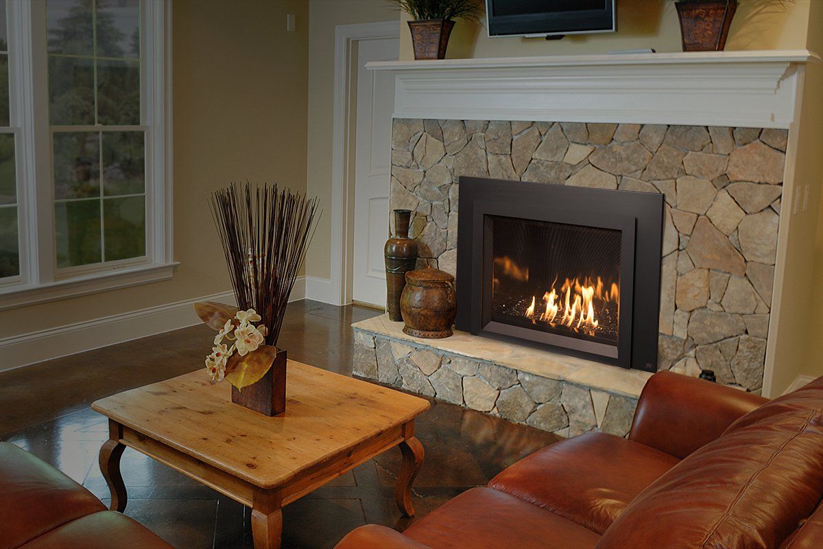 Living room with a lit fireplace, stone hearth, brown leather couch, and wooden coffee table.