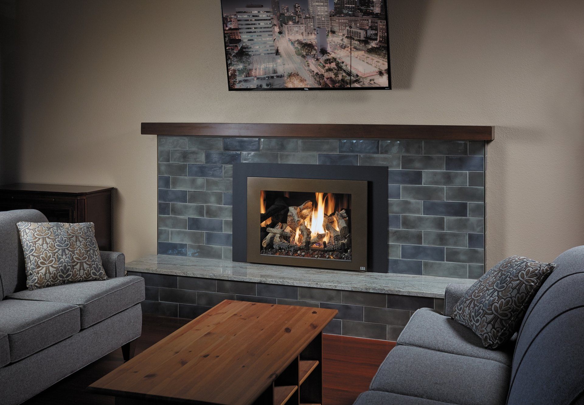 Fireplace with blue stone surround, lit fire, and two gray sofas in a living room.