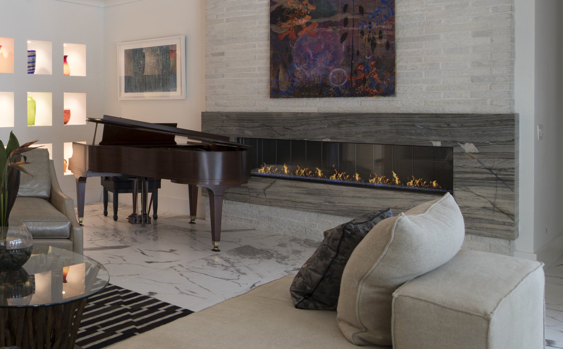 Living room with grand piano, fireplace, modern furniture, artwork, and recessed shelving.