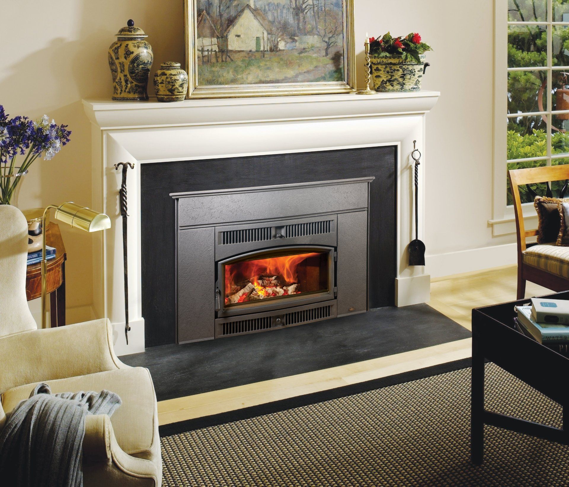 Fireplace with a lit fire, surrounded by a white mantel and black hearth.