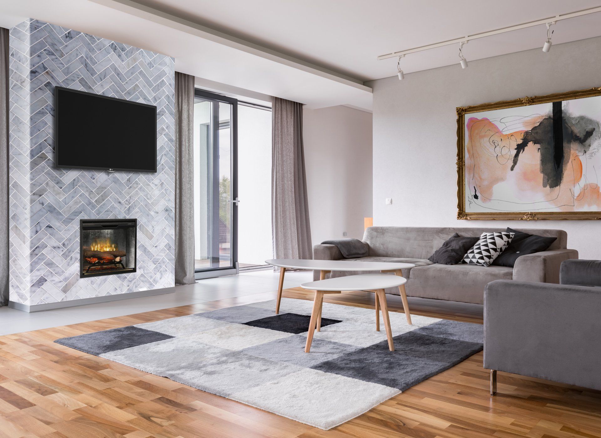 Modern living room with a fireplace, TV, sofa, and art. Wooden floor with area rug.