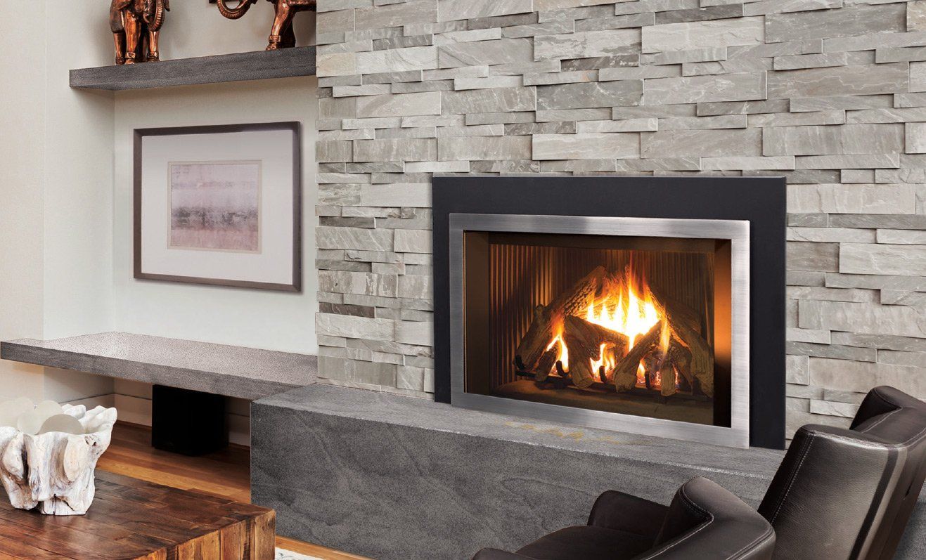 Fireplace with gray stone surround and fire burning, with artwork and seating nearby.