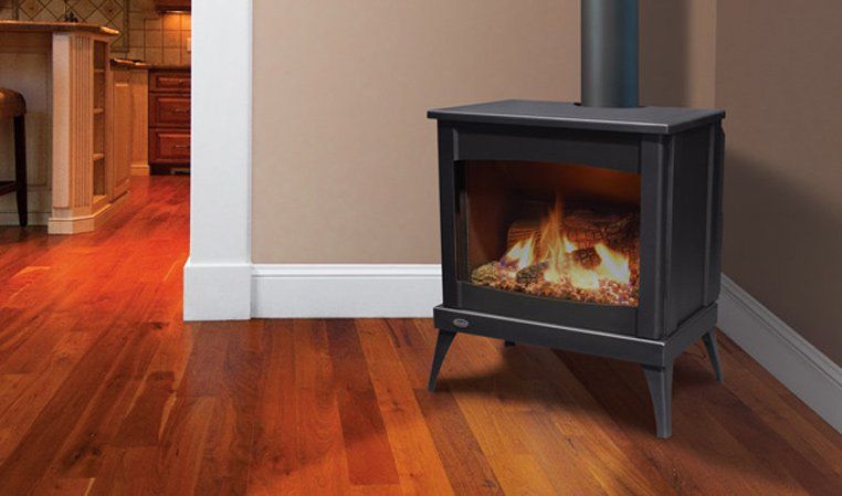 Black gas fireplace with flames, metal chimney, set against a brown wall and wooden floor.