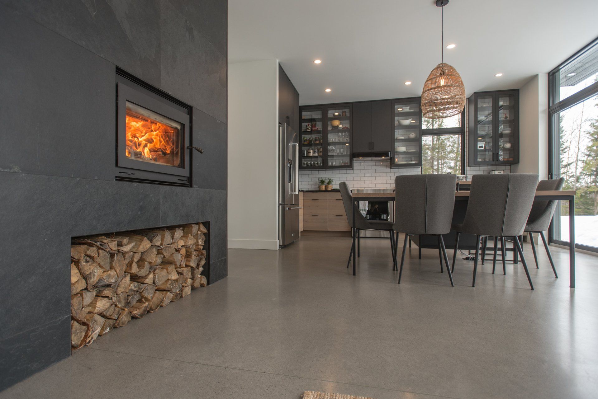 Modern kitchen and dining room with fireplace and wood storage.