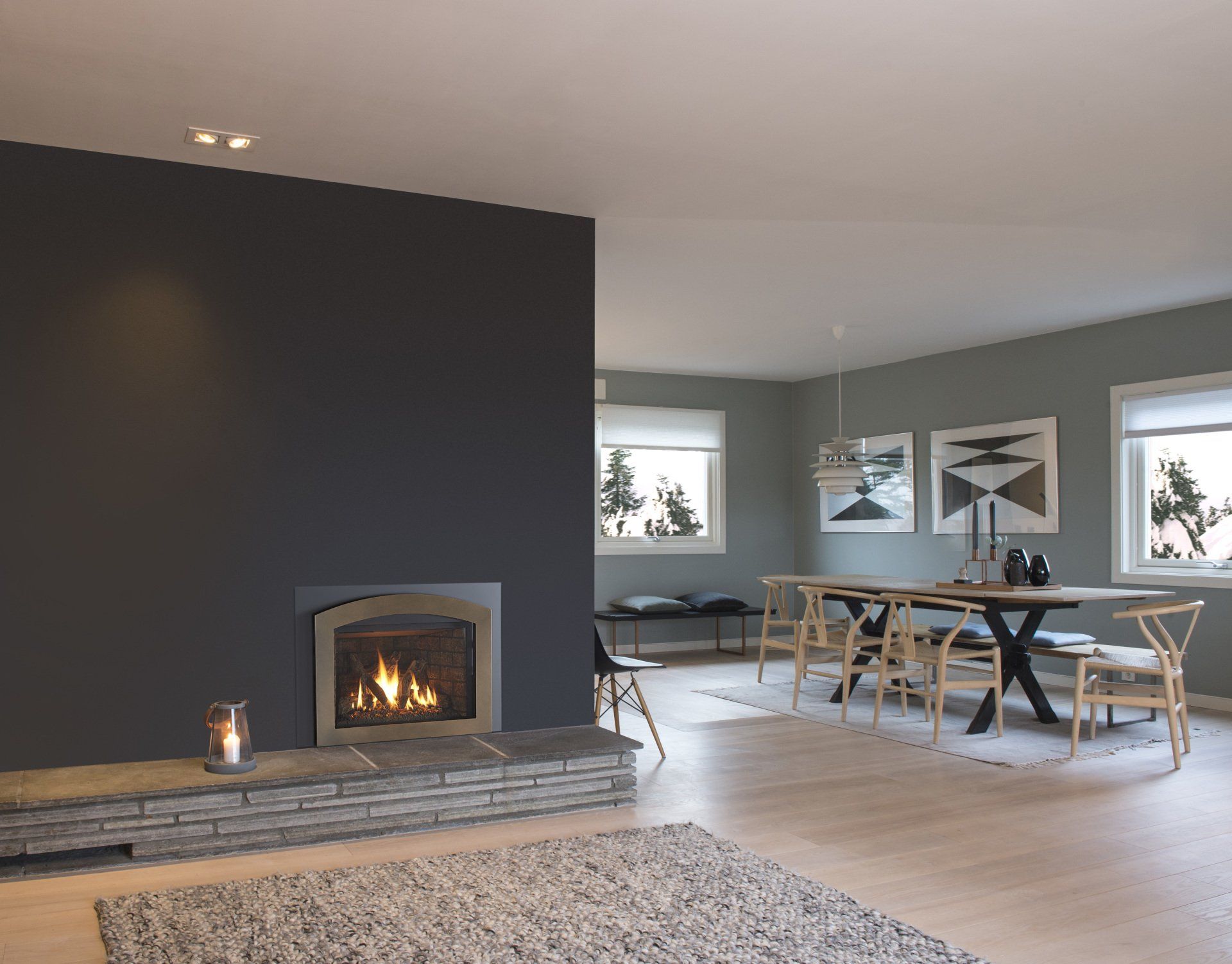 Modern living room with a fireplace, dining area, and a large dark gray accent wall.