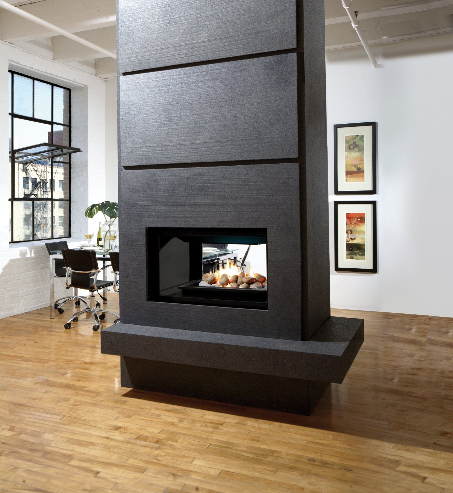 Modern black fireplace in a room with hardwood floors, a window, and artwork.