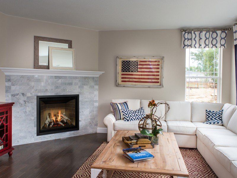 Cozy living room with fireplace, white sectional sofa, rustic coffee table, and American flag art.