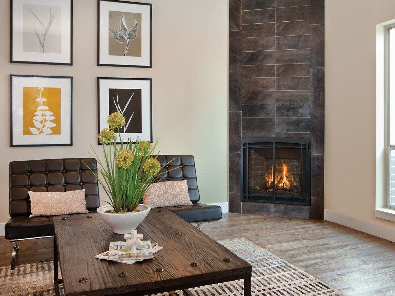 Living room with fireplace, two black chairs, wooden coffee table, and framed art. Beige walls and tiled fireplace.