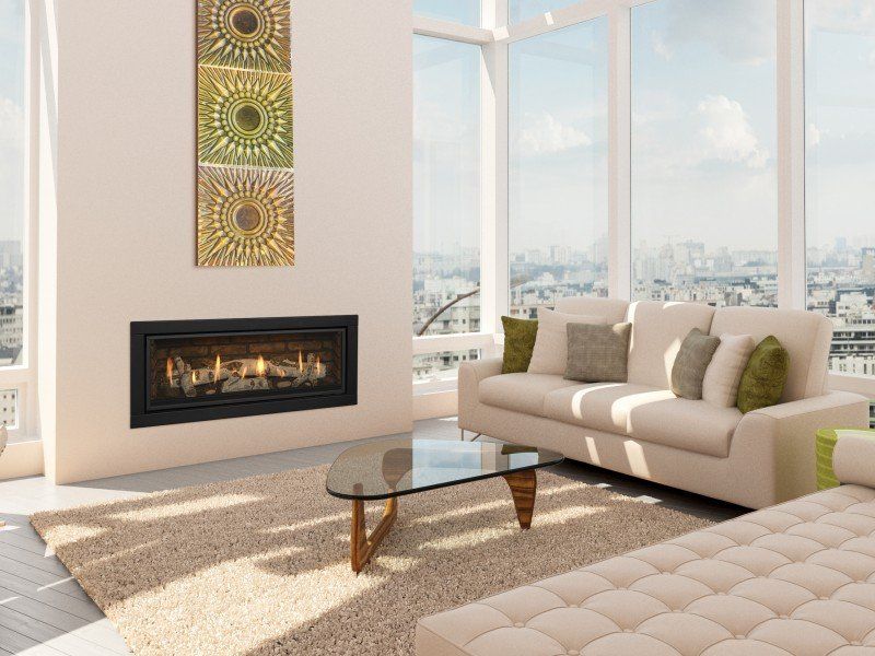 Living room with fireplace, cream sofa, and city view through large windows.