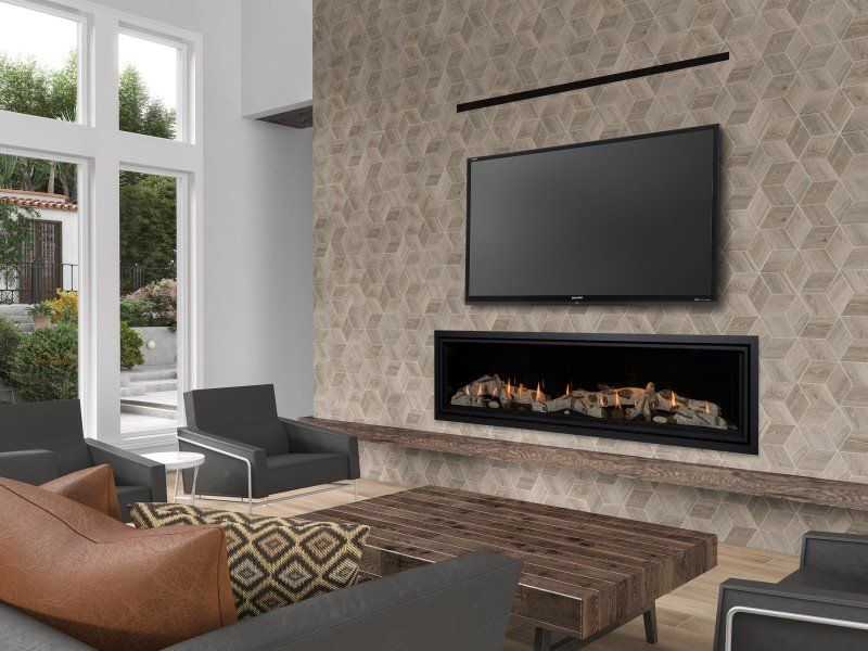 Living room with fireplace, TV on textured wall, sofa, armchairs, and a large window with outdoor view.