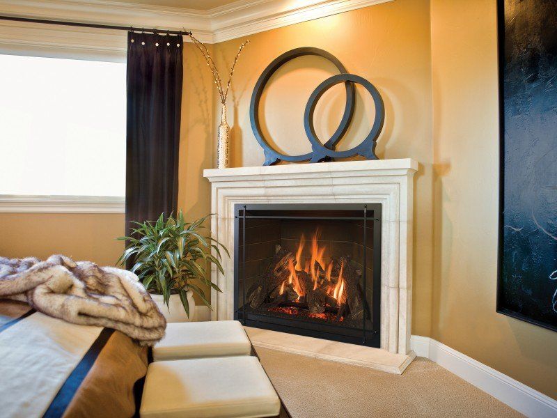 Corner fireplace with flames, cream mantel, black metal screen, and gold wall.