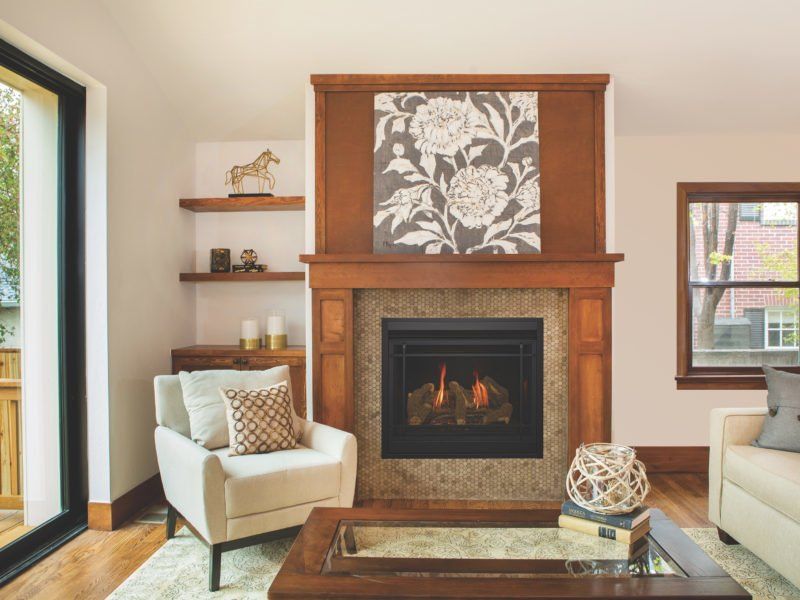 Cozy living room with fireplace, floral art, cream-colored armchair, and floating shelves.