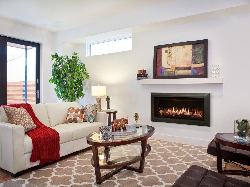 Cozy living room with fireplace, white sofa, red blanket, and patterned rug.