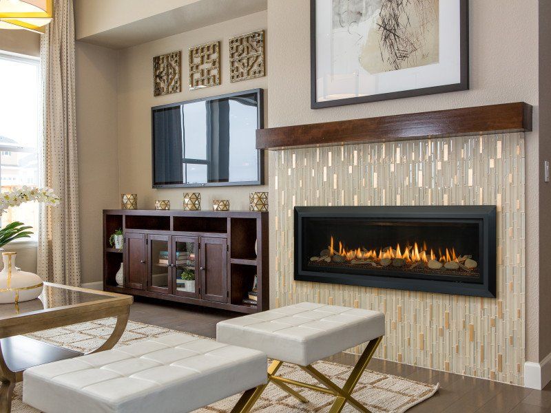 Living room with fireplace, TV, and seating, featuring neutral colors, warm lighting, and decorative elements.