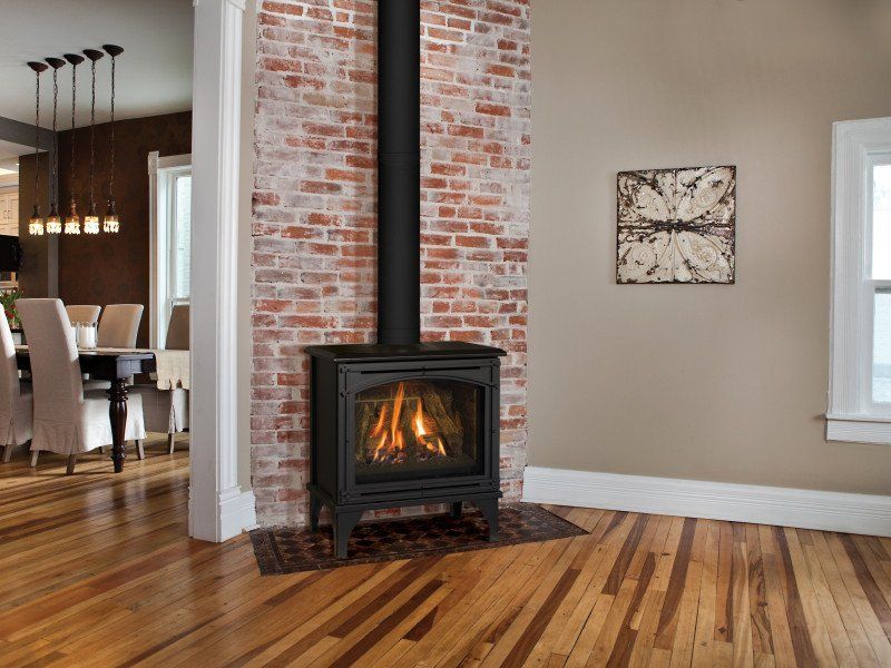 Fireplace with brick chimney in a room with hardwood floors, a connecting dining area and neutral walls.
