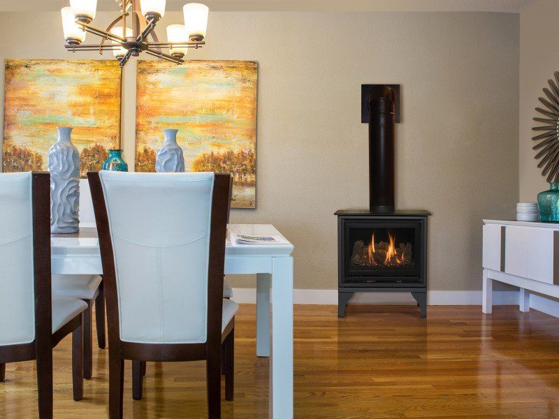 Dining room with gas stove, white table, chairs, art, and wood floors.