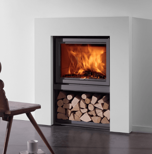 Modern fireplace with flames burning, wood storage below, white surround, and a wooden chair.