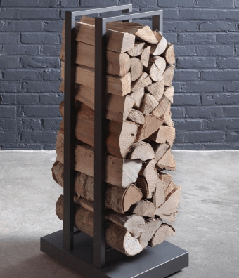 Metal firewood rack filled with stacked logs against a dark brick wall.