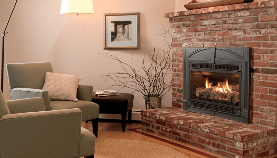 Cozy living room with brick fireplace, armchairs, lamp, and framed artwork.