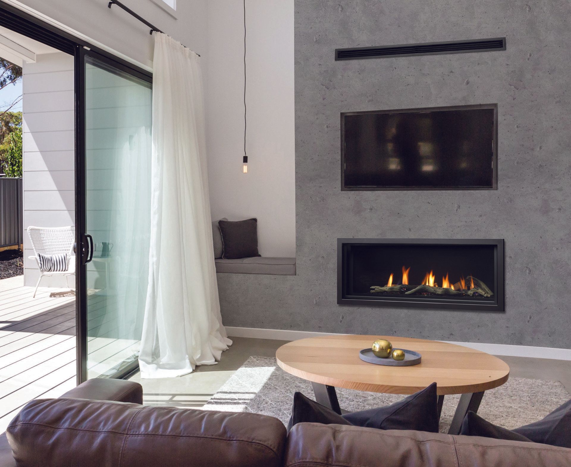 Modern living room with fireplace, TV, and sliding glass door. Gray concrete wall, neutral decor, light wood table.
