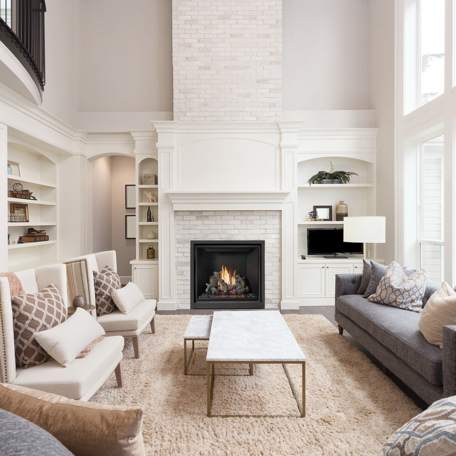 Living room with fireplace, built-in shelves, sofa, chairs, and marble coffee table; neutral colors, well-lit.