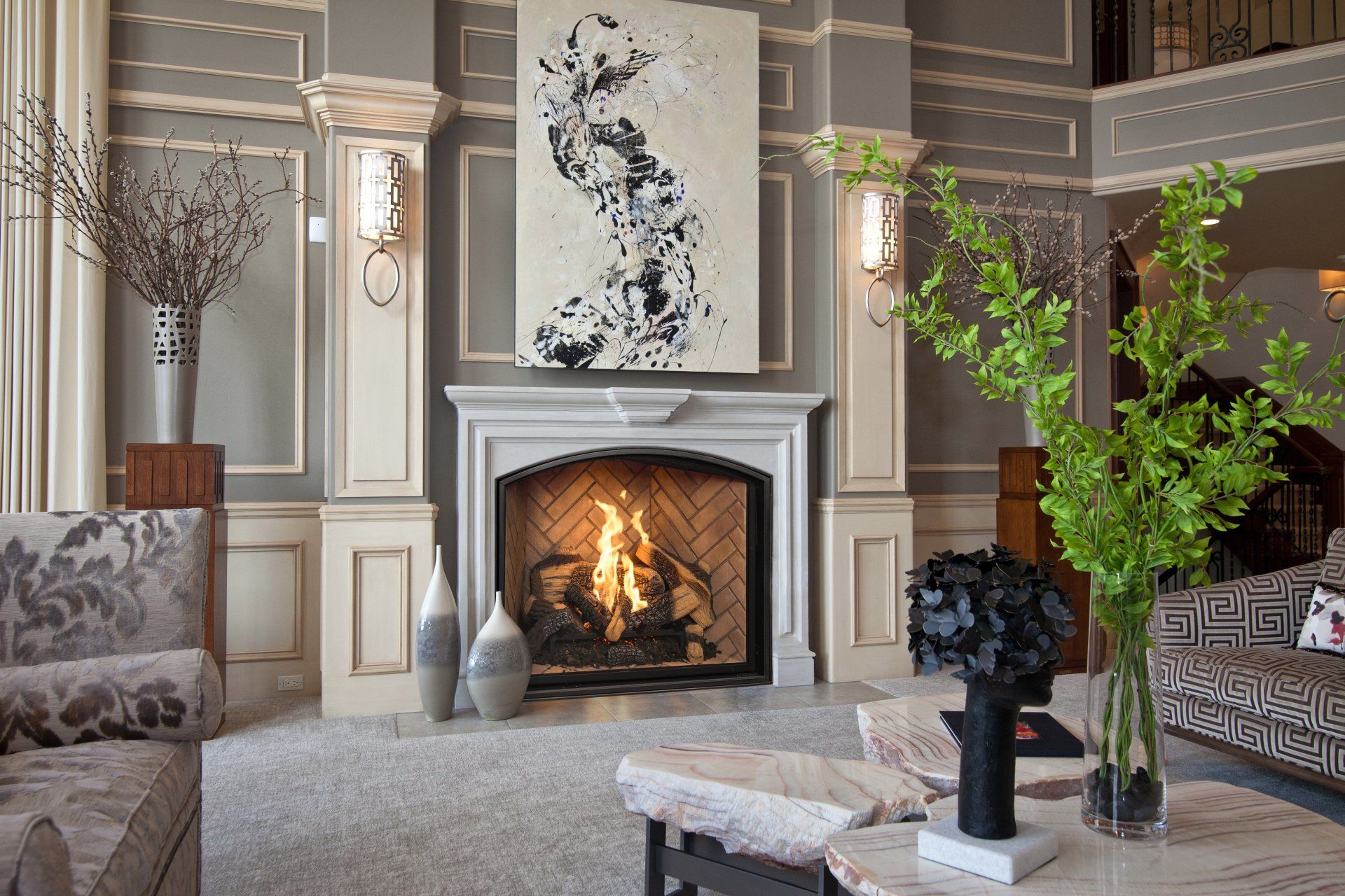 Living room with fireplace, abstract art, light gray walls, plush seating, and decorative vases.