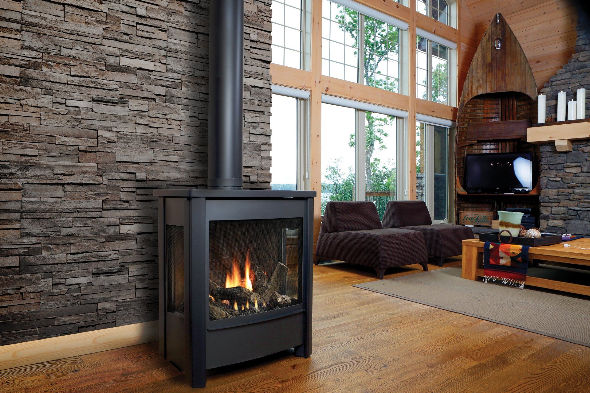 Black gas fireplace in modern living room with exposed brick wall and large windows.