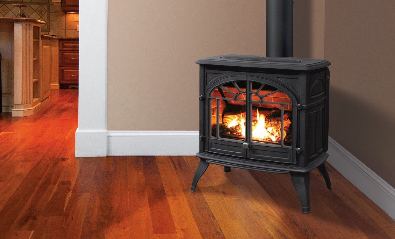 A black cast iron wood-burning stove with a lit fire sits in a corner, next to a hardwood floor.