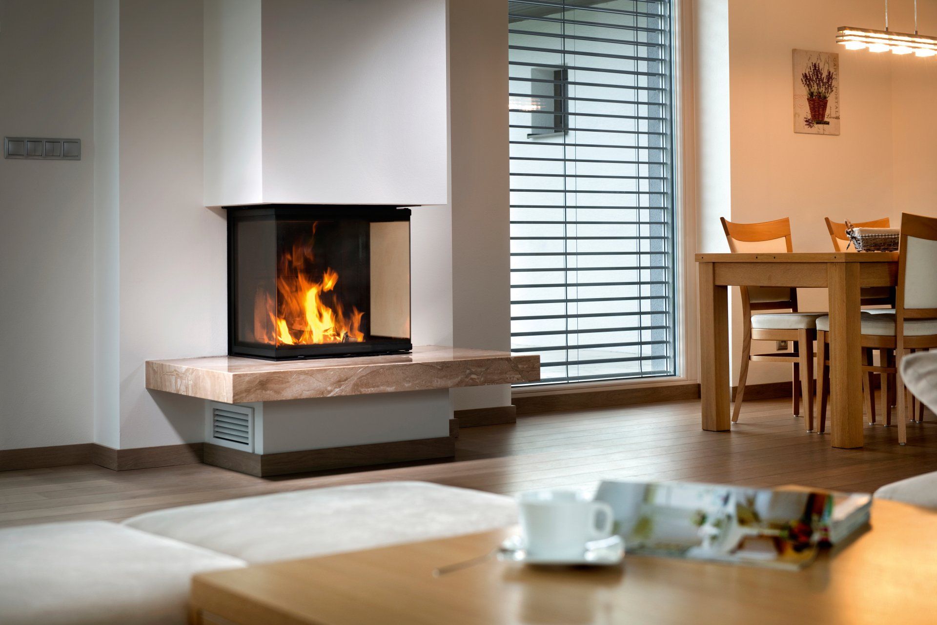 Corner fireplace with flames, stone base, and glass viewing panels in a modern living room.