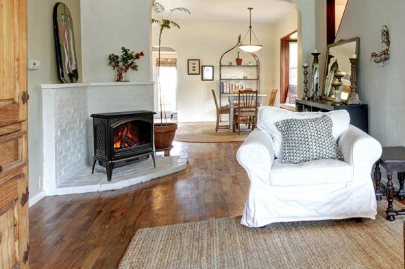 Living room with fireplace, white armchair, rug, and arched doorways to dining area.