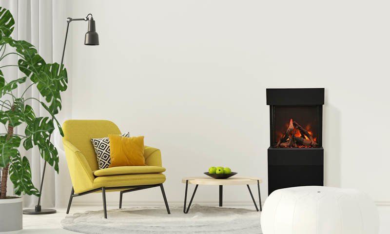 Yellow chair with pillows, floor lamp, small table, fireplace, and large plant.