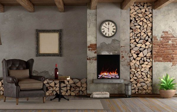 Cozy living room with fireplace, logs, armchair, framed art, and clock on a rustic brick and wood wall.