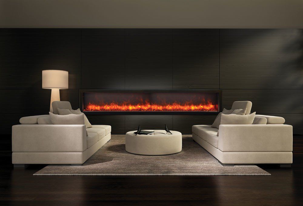 Modern living room with fireplace, two sofas facing each other, coffee table, and lamp against a dark wall.